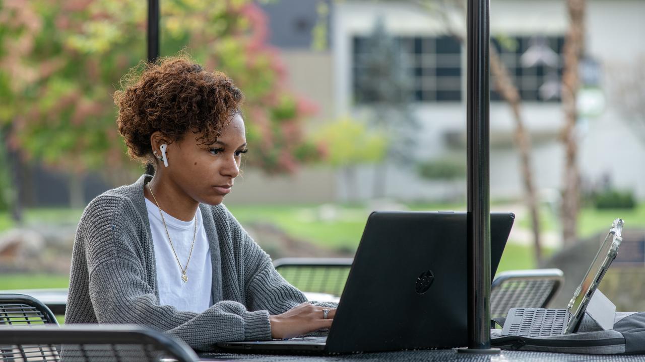 Student working on laptop next to large window