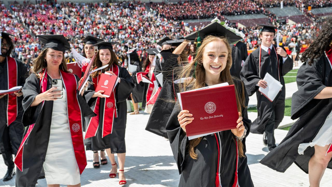 Multiple graduates presenting their diplomas at the Satdium