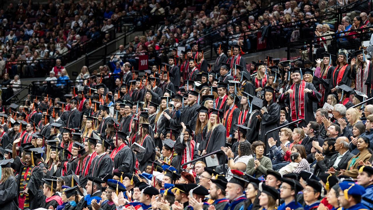 A large group of graduates moving forward to graduate